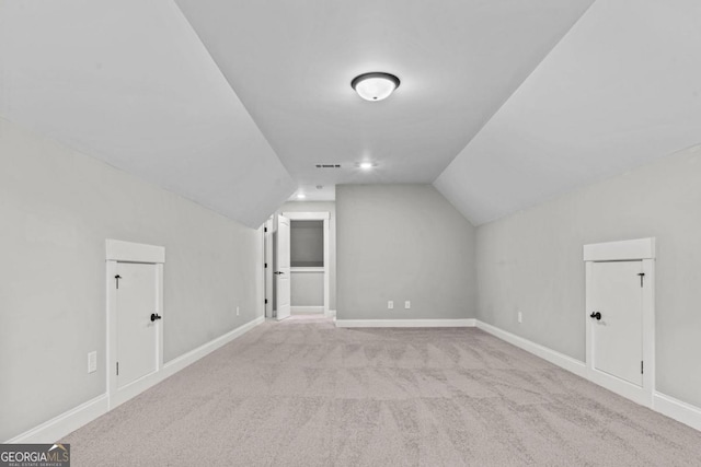 bonus room with vaulted ceiling and light carpet