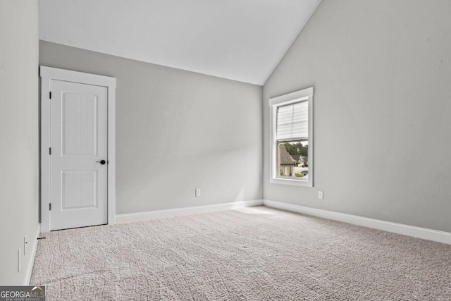 carpeted spare room with vaulted ceiling