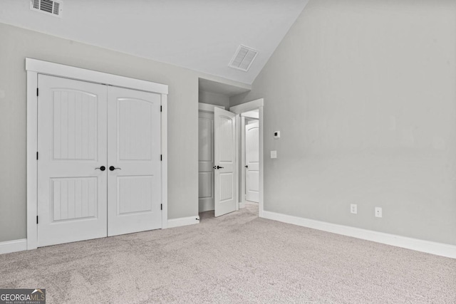 unfurnished bedroom featuring light colored carpet, lofted ceiling, and a closet