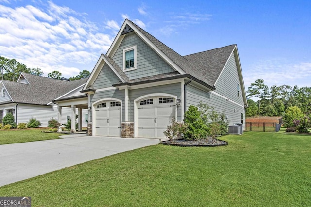 craftsman house featuring cooling unit, a garage, and a front lawn