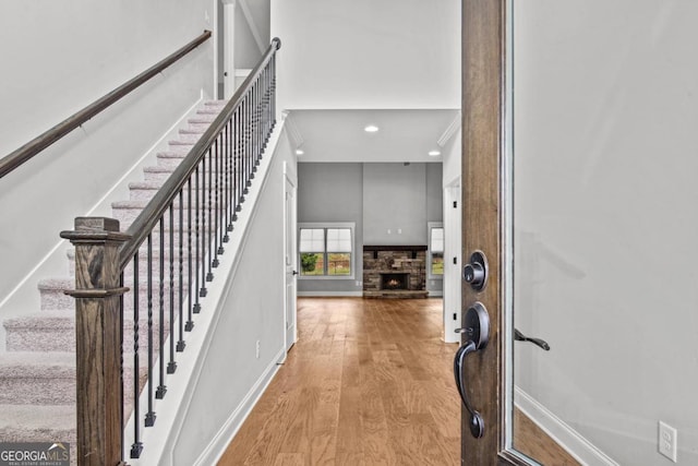 stairs with hardwood / wood-style floors, a towering ceiling, and a fireplace