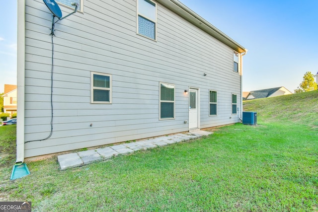 rear view of house with central AC and a yard