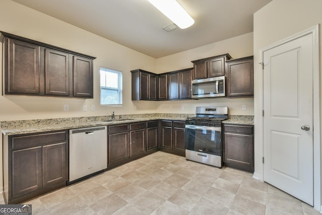 kitchen featuring light stone counters, appliances with stainless steel finishes, sink, and dark brown cabinets