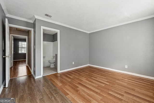 unfurnished bedroom featuring ornamental molding, wood-type flooring, and connected bathroom