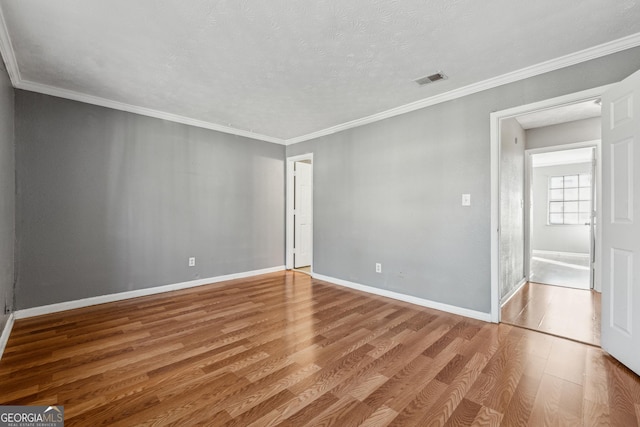 empty room featuring hardwood / wood-style flooring, ornamental molding, and a textured ceiling