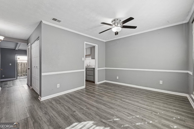 spare room featuring crown molding, dark wood-type flooring, a textured ceiling, and ceiling fan