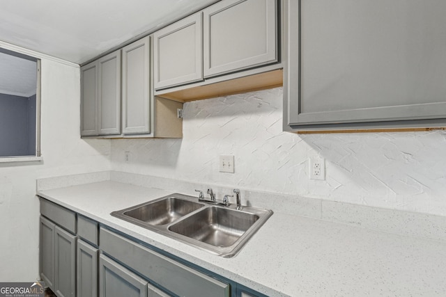 kitchen with gray cabinetry, sink, and tasteful backsplash