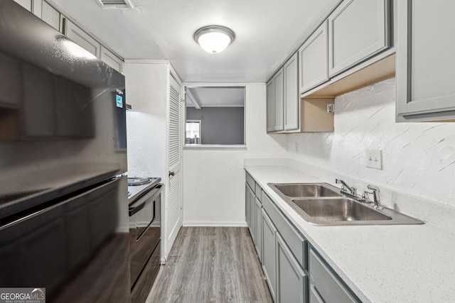 kitchen with gray cabinetry, sink, electric range oven, and light hardwood / wood-style floors