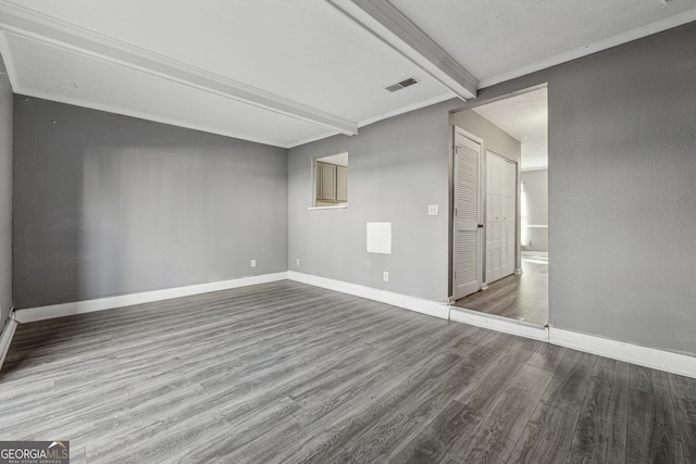 empty room with crown molding, hardwood / wood-style floors, and beam ceiling