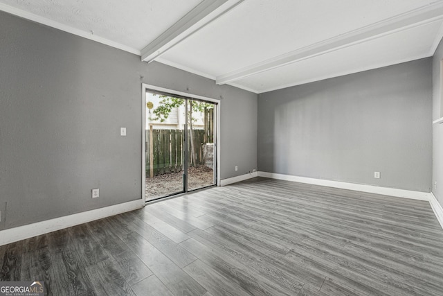 spare room featuring dark hardwood / wood-style flooring, ornamental molding, and beam ceiling