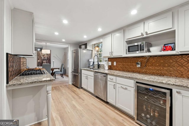 kitchen featuring wine cooler, white cabinetry, light stone counters, decorative light fixtures, and appliances with stainless steel finishes