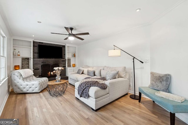 living room with built in shelves, plenty of natural light, a brick fireplace, and light wood-type flooring