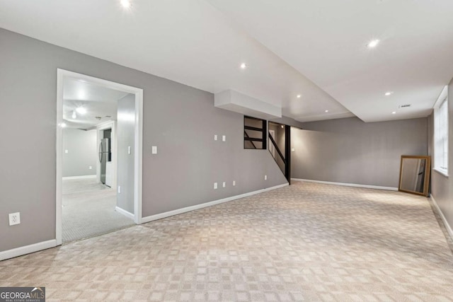 basement with light colored carpet and stainless steel refrigerator