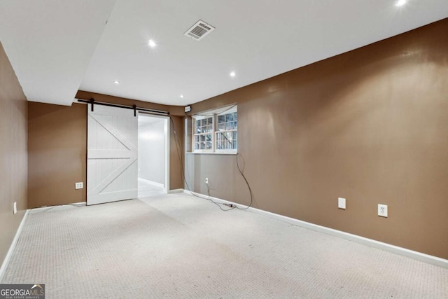 spare room featuring a barn door and carpet flooring