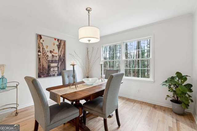 dining area with crown molding and light hardwood / wood-style floors