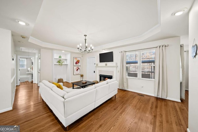 living room featuring a raised ceiling, ornamental molding, plenty of natural light, and hardwood / wood-style flooring