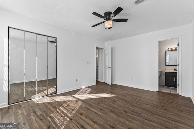 unfurnished bedroom with dark hardwood / wood-style flooring, connected bathroom, sink, and a textured ceiling