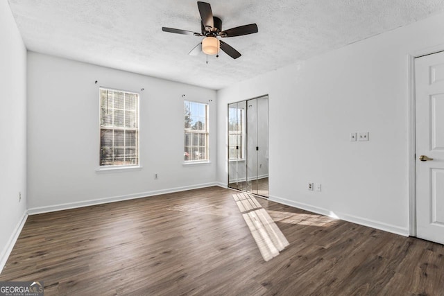 spare room featuring ceiling fan, dark wood-type flooring, and a textured ceiling