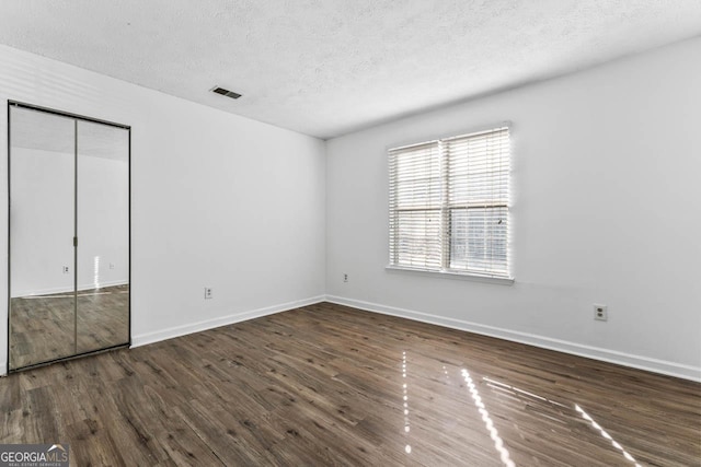 unfurnished bedroom featuring dark hardwood / wood-style flooring, a closet, and a textured ceiling