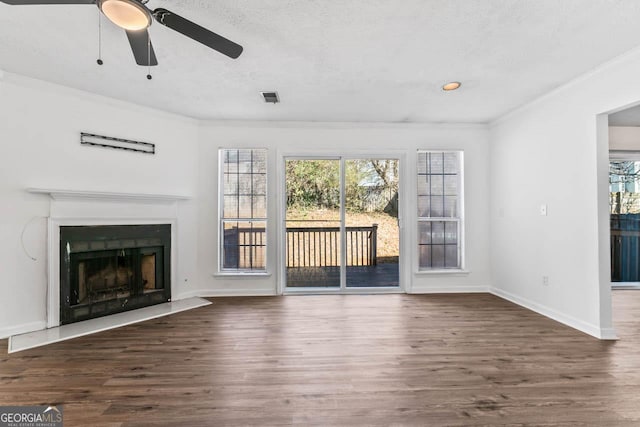 unfurnished living room featuring crown molding, plenty of natural light, and dark hardwood / wood-style flooring