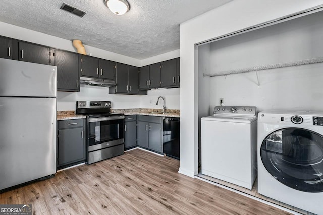 kitchen with sink, light hardwood / wood-style flooring, washer and dryer, and appliances with stainless steel finishes