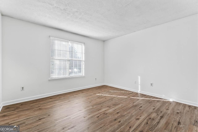 spare room featuring dark hardwood / wood-style floors and a textured ceiling