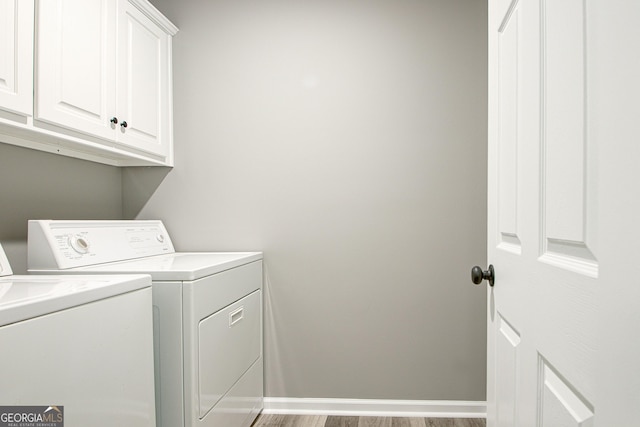 clothes washing area with light hardwood / wood-style flooring, washer and clothes dryer, and cabinets