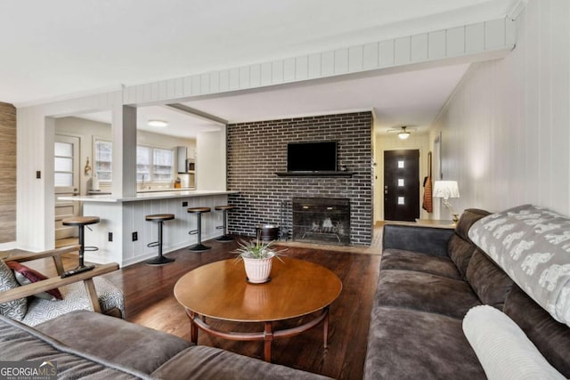 living room featuring beam ceiling, hardwood / wood-style floors, and a brick fireplace