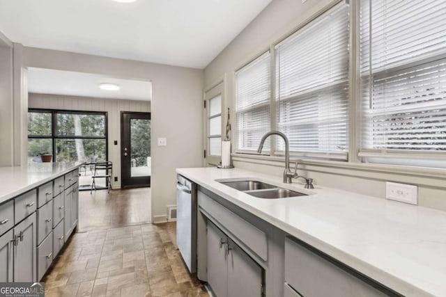 kitchen featuring dishwasher, sink, and gray cabinetry