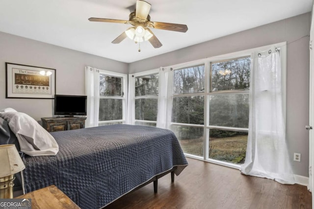 bedroom with ceiling fan, dark hardwood / wood-style flooring, and multiple windows