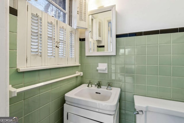 bathroom featuring tile walls, sink, plenty of natural light, and toilet