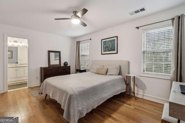 bedroom with ceiling fan, ensuite bathroom, and light hardwood / wood-style floors