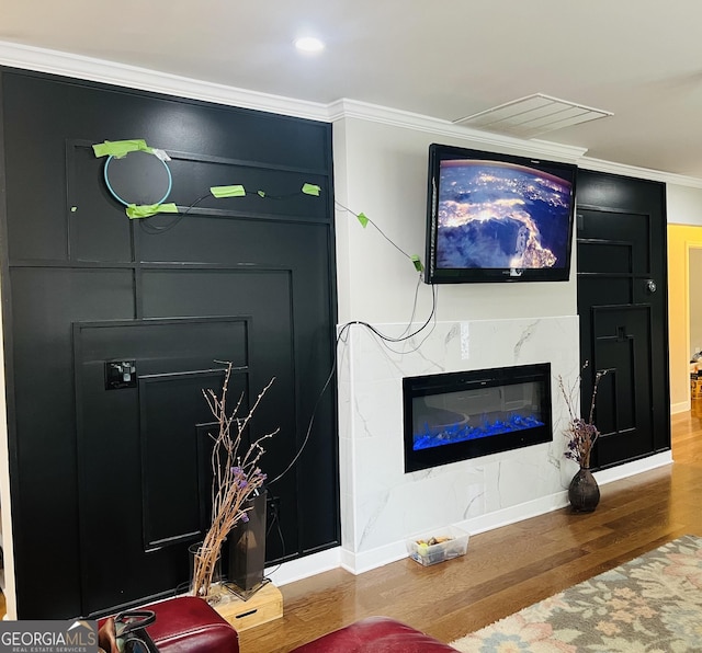 living room featuring hardwood / wood-style flooring, ornamental molding, and a premium fireplace