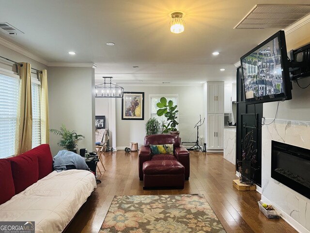 living room featuring crown molding, wood-type flooring, and a high end fireplace