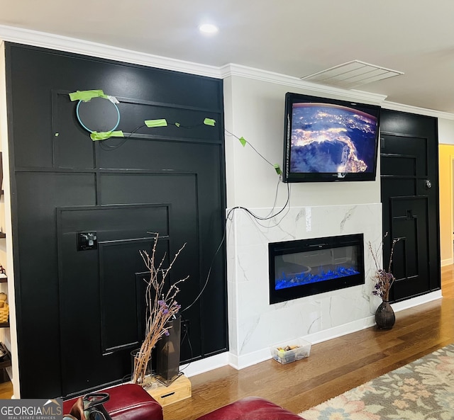 living room with crown molding, a premium fireplace, and hardwood / wood-style floors