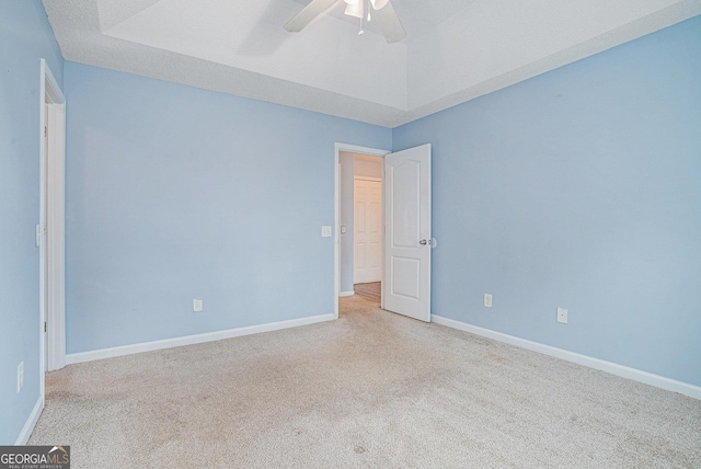 spare room featuring light carpet, vaulted ceiling, and ceiling fan