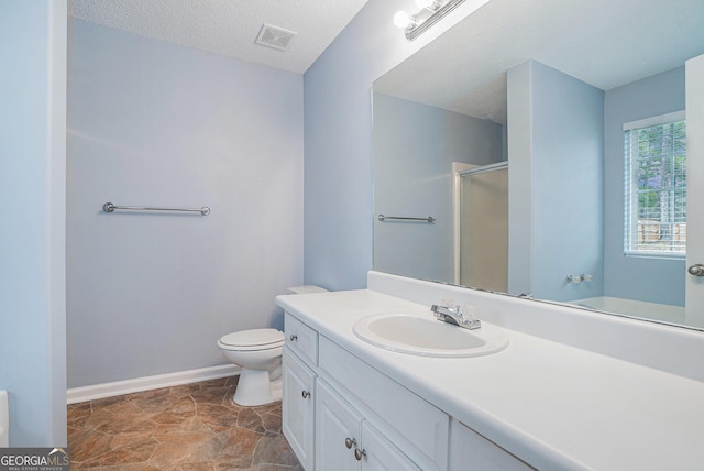 bathroom with vanity, a textured ceiling, toilet, and walk in shower