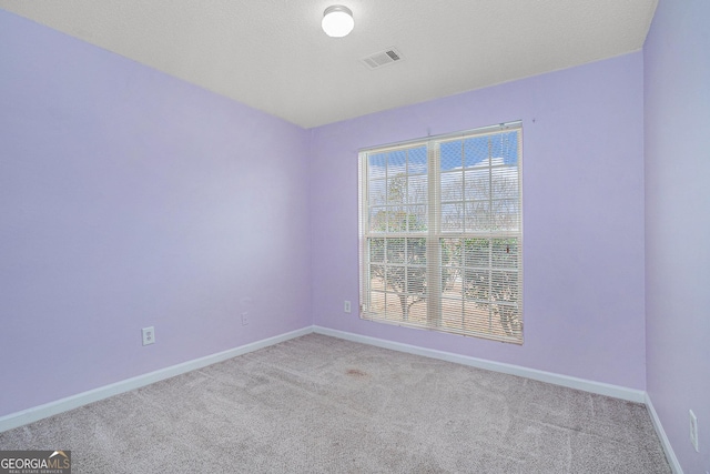 unfurnished room featuring light carpet and a textured ceiling