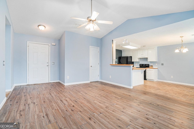 unfurnished living room with vaulted ceiling, ceiling fan with notable chandelier, and light hardwood / wood-style floors