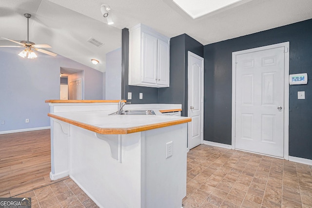 kitchen with white cabinetry, sink, kitchen peninsula, and a breakfast bar