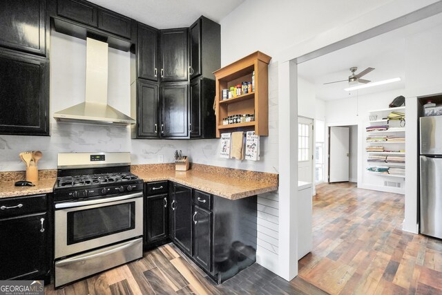 kitchen featuring light stone counters, appliances with stainless steel finishes, light hardwood / wood-style floors, and wall chimney range hood