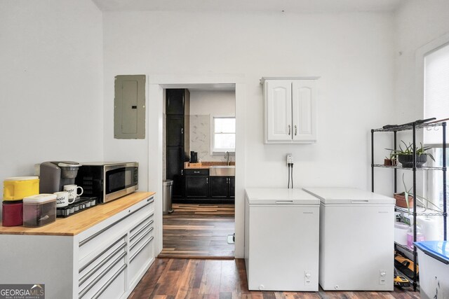 laundry room featuring sink, dark wood-type flooring, electric panel, and washing machine and clothes dryer