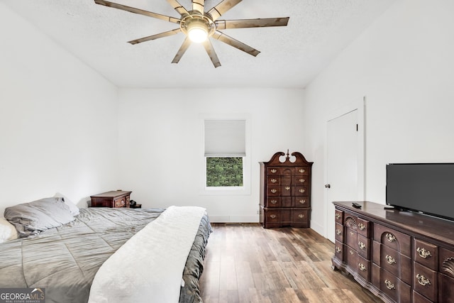 bedroom with hardwood / wood-style flooring, ceiling fan, and a textured ceiling