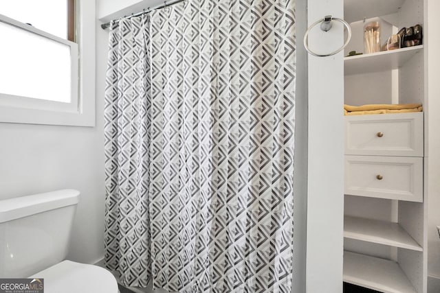 bathroom featuring walk in shower and toilet