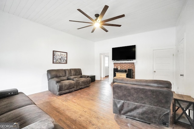 living room with hardwood / wood-style floors, ceiling fan, and a brick fireplace