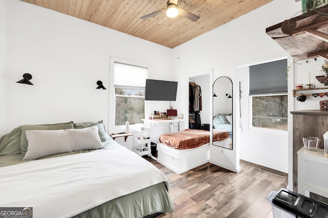 bedroom featuring wood-type flooring, a spacious closet, wooden ceiling, and ceiling fan