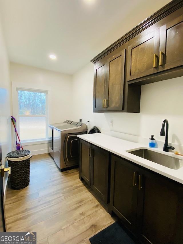 washroom featuring light hardwood / wood-style floors, cabinets, separate washer and dryer, and sink