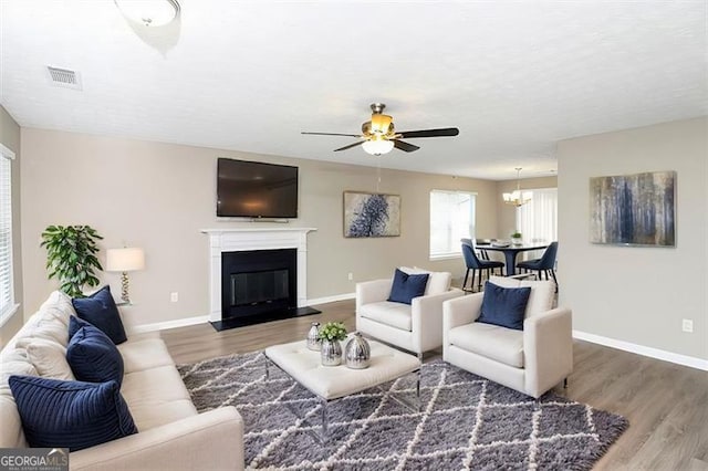 living room featuring ceiling fan with notable chandelier and wood-type flooring