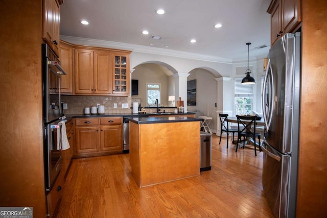 kitchen with decorative light fixtures, sink, decorative backsplash, a center island, and stainless steel appliances