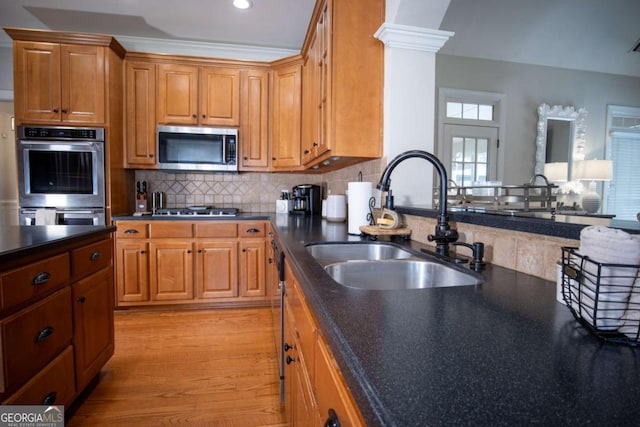 kitchen featuring appliances with stainless steel finishes, decorative columns, tasteful backsplash, sink, and light hardwood / wood-style floors